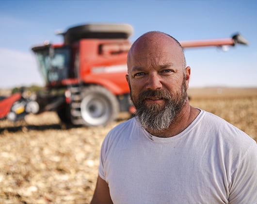 Male standing in front of tractor in a corn field